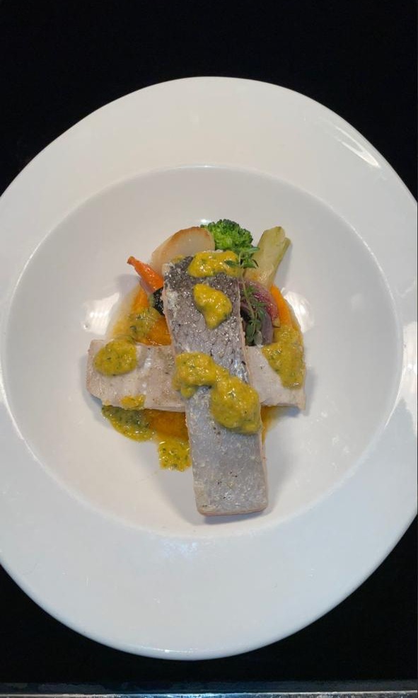 Plated fish fillets with herb citrus sauce and roasted vegetables